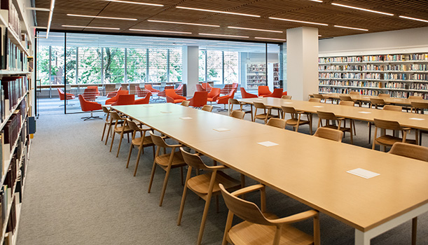 The current Reading Room in the Skokie Public Library, showing long wooden tables with wooden chairs, bookshelf-lined walls, and low orange chairs along a floor to ceiling wall of glass that looks out on the second floor of the library. The current Reading Room in the Skokie Public Library, showing long wooden tables with wooden chairs, bookshelf-lined walls, and low orange chairs along a floor to ceiling wall of glass that looks out on the second floor of the library.