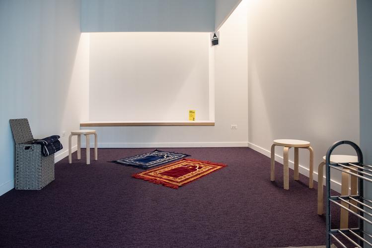 A room with prayer rugs and stool seating A room with prayer rugs and stool seating