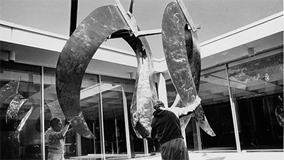 Sculptor Elliott Balter guides sculpture as it is lowered into the Water Court