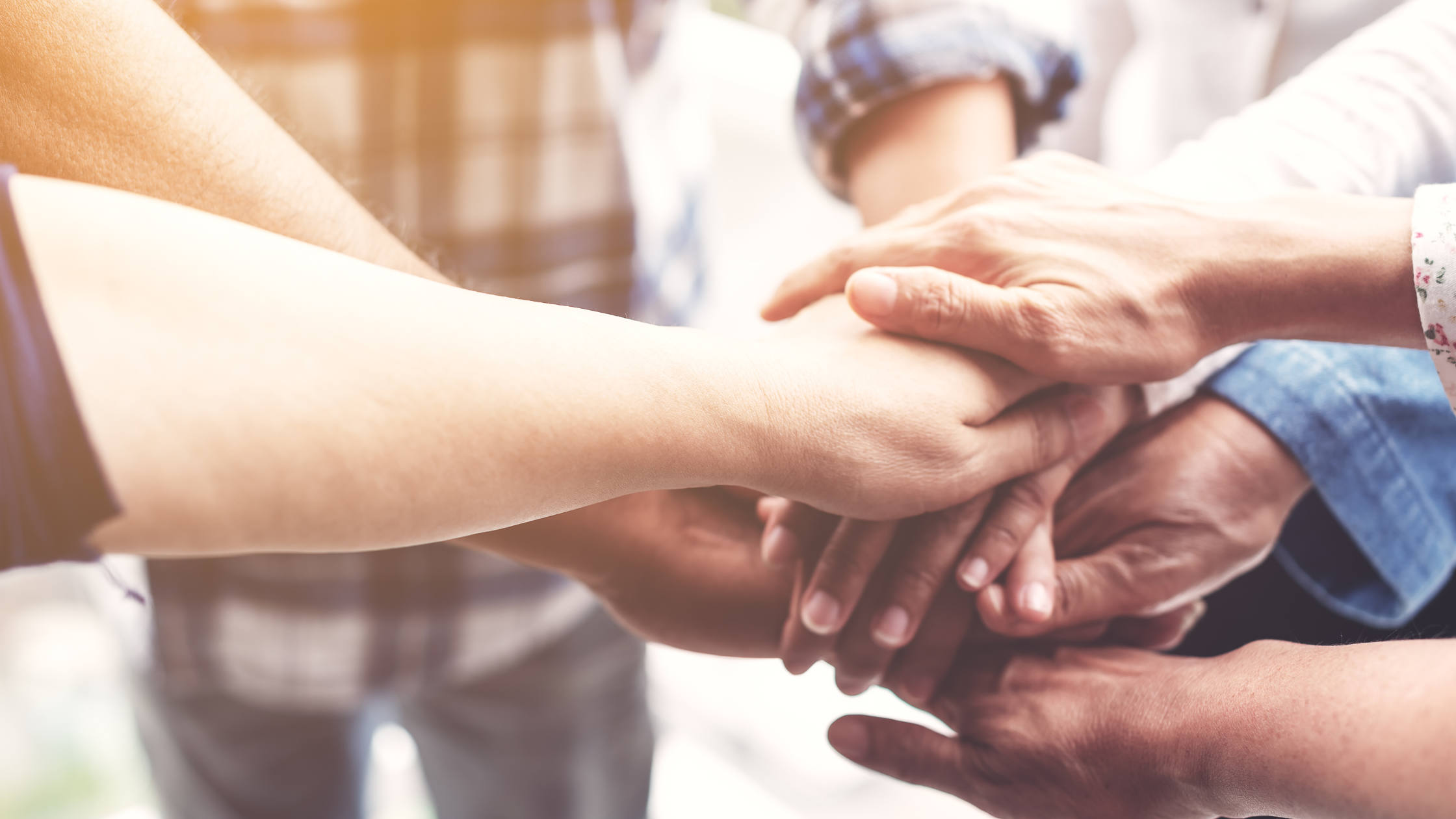 People placing their hands on top of each other in a gesture of teamwork