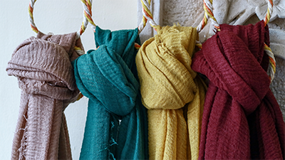 Four different colored scarves hung up on scarf rings