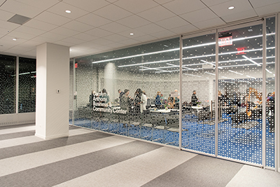 Glass room with dots covering the windows and text reading 'Carolyn A. Anthony Business & Community Center'. People standing inside the glass room.