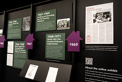 shot of a physical exhibit displaying fair housing in the 1960s. There are pamphlets and images from that time.