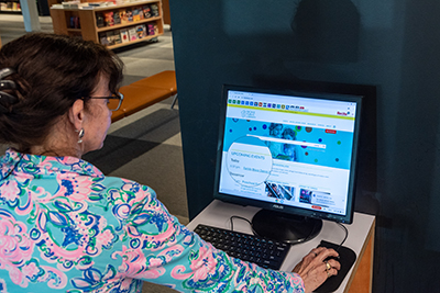 woman operating a computer. The magnifying glass tool is on the homepage of the screen
