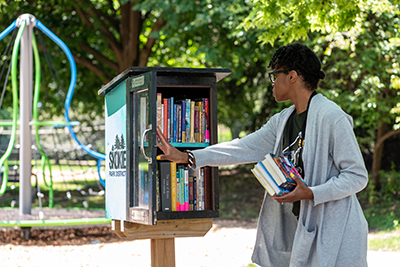 Library staff person putting books in a Little Free Library
