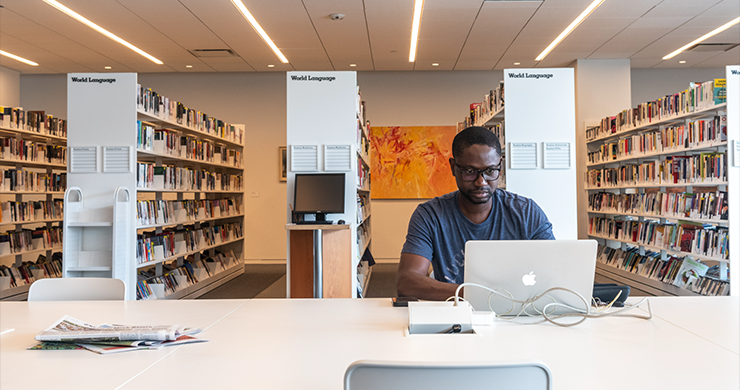 Man sitting in the library with an open laptop
