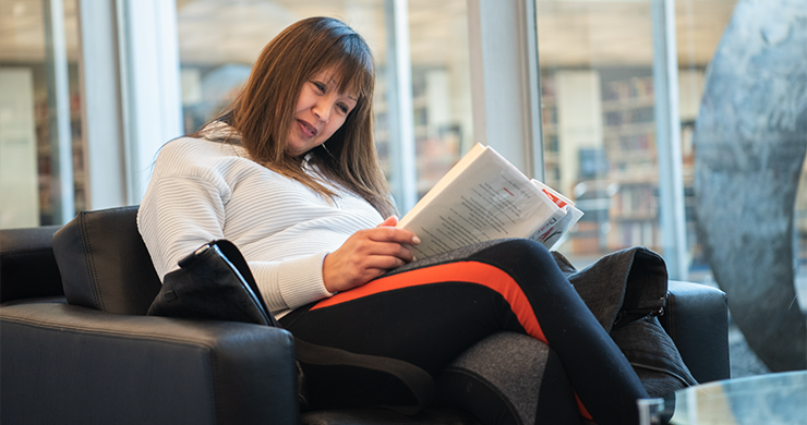 Woman reading while sitting in a comfortable chair in the library