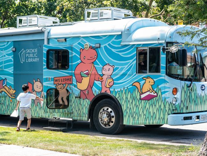 Young boy standing beside the colorful Bookmobile