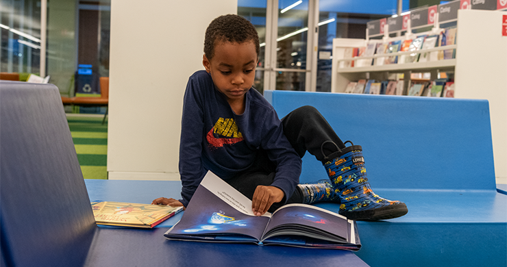 Young boy sitting in the library with an open book