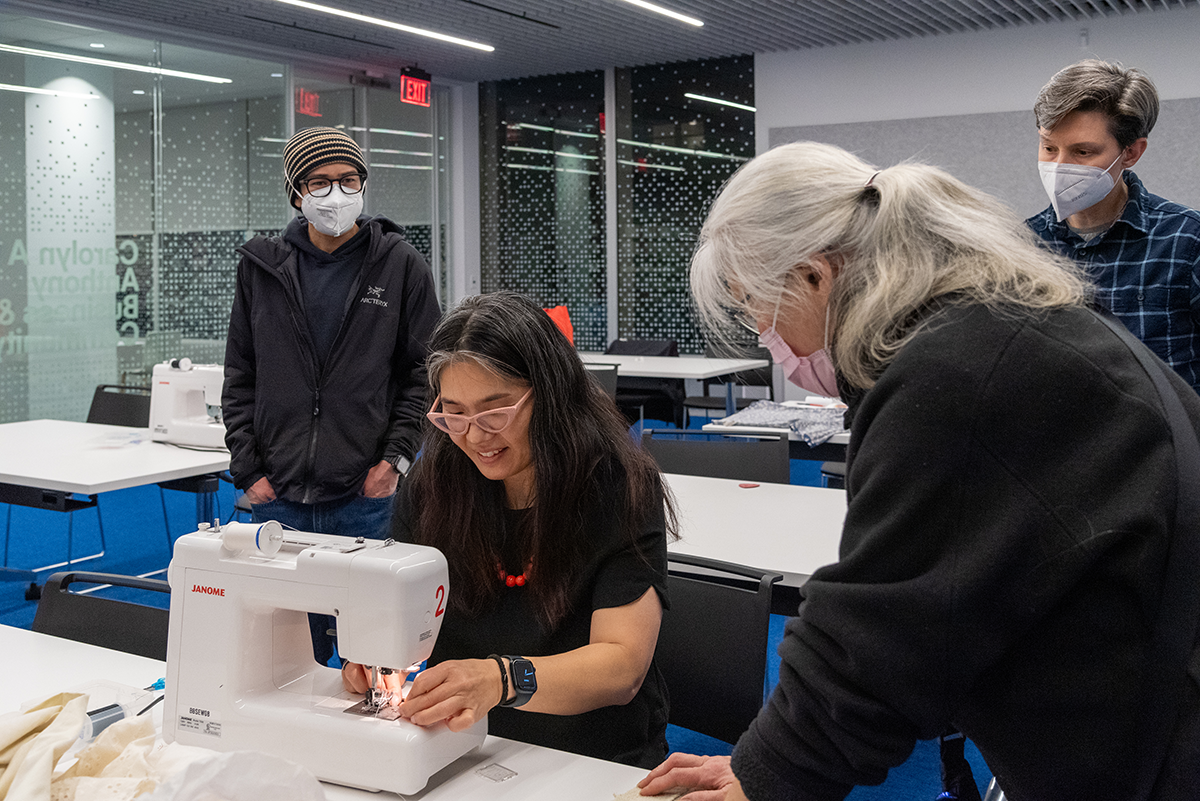 Julie Oh helping a woman with her sewing machine during a Maker event