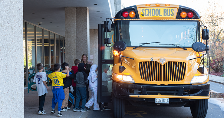 Teacher helping students onto a school bus