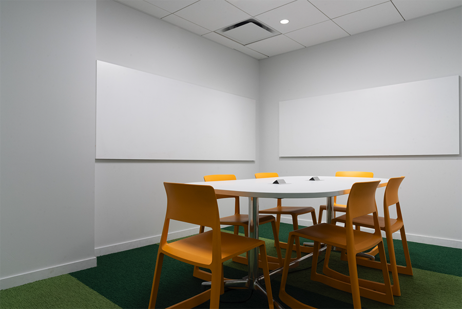 Empty study room with two whiteboards and yellow chairs around a white table