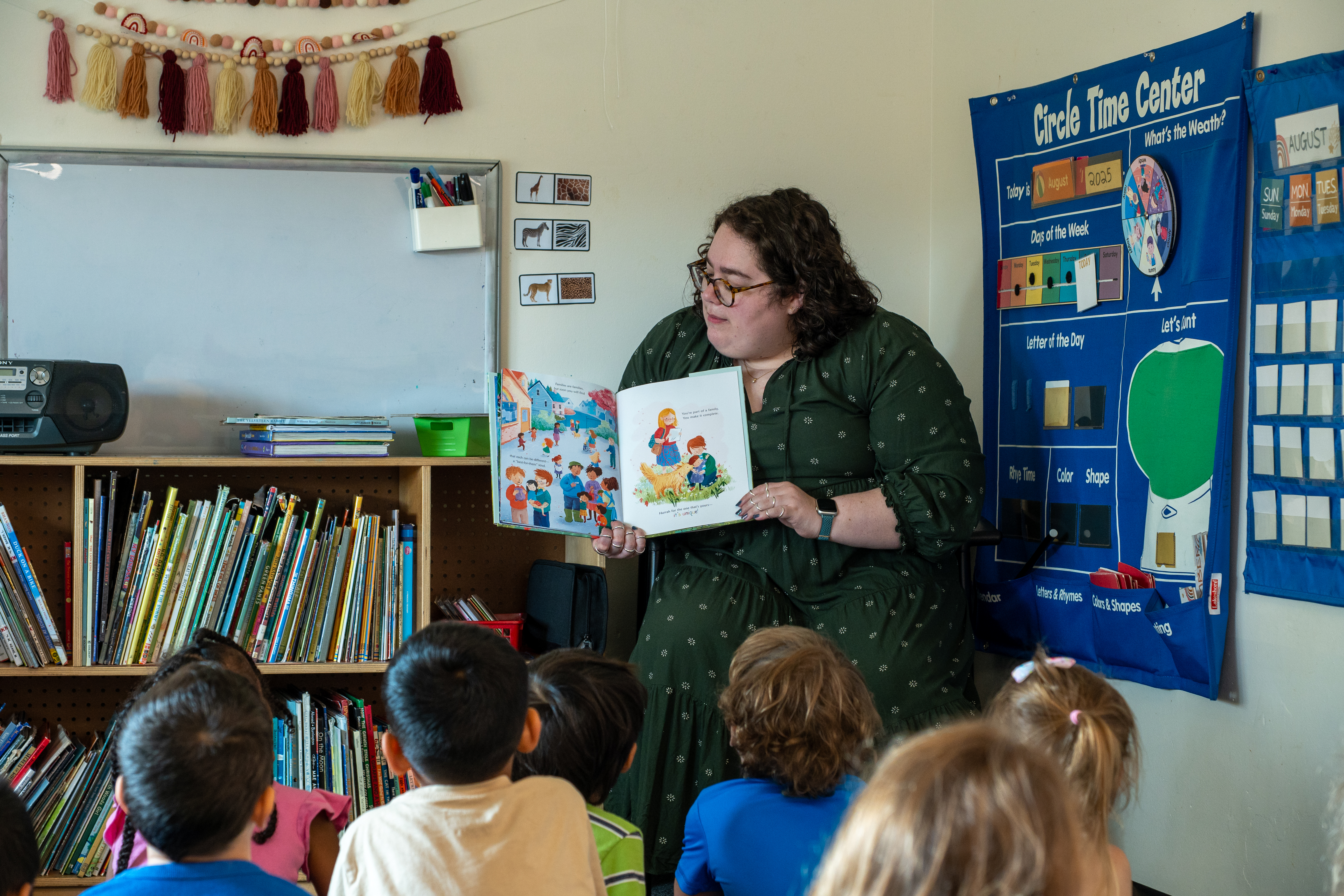 female staff member reading a picture book to young children