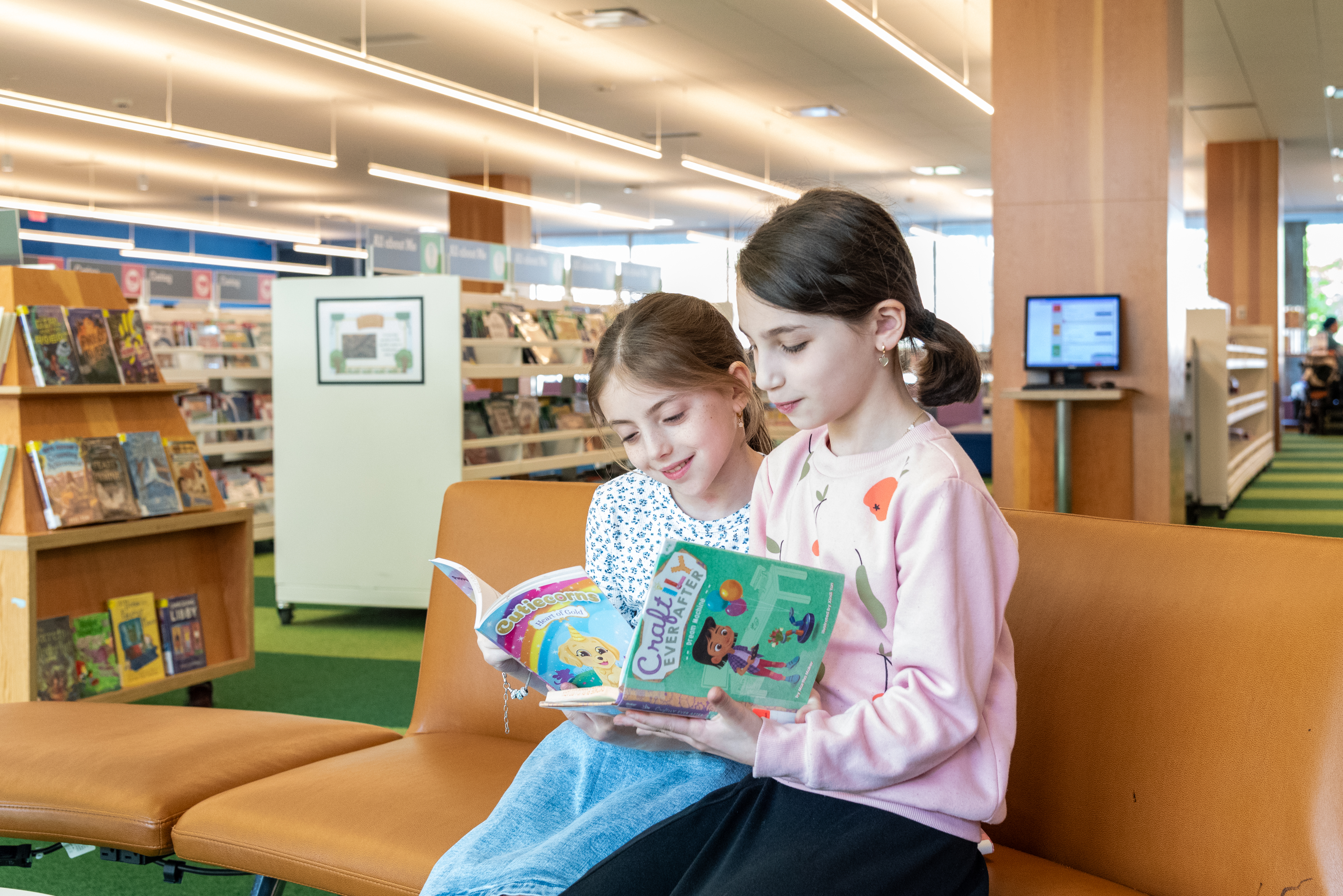 two young girls seated and reading books
