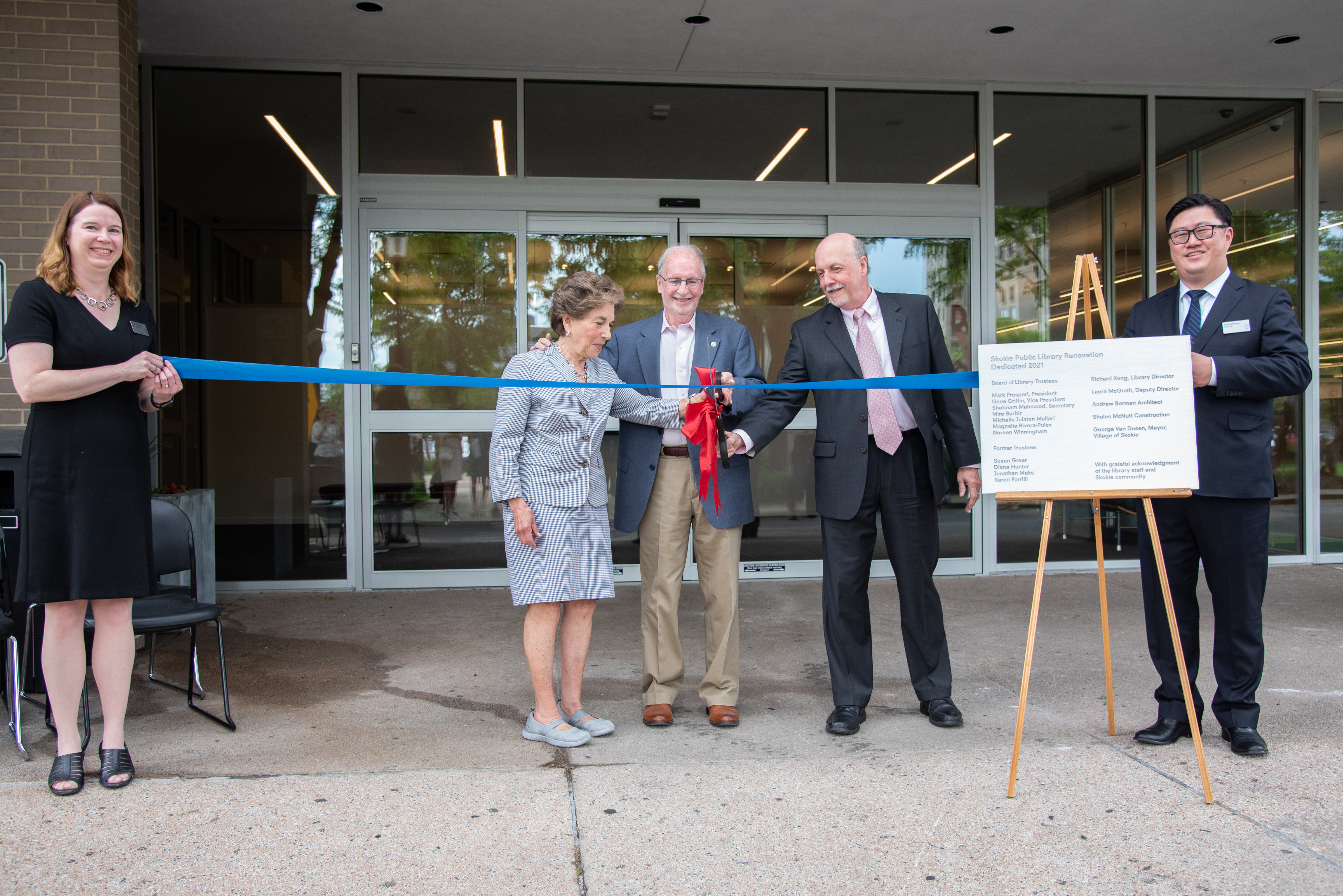 Gene, assisted by Mayor George Van Dusen and Congresswoman Jan Schakaowsky, cuts a ribbon to dedicate the renovated library in 2021