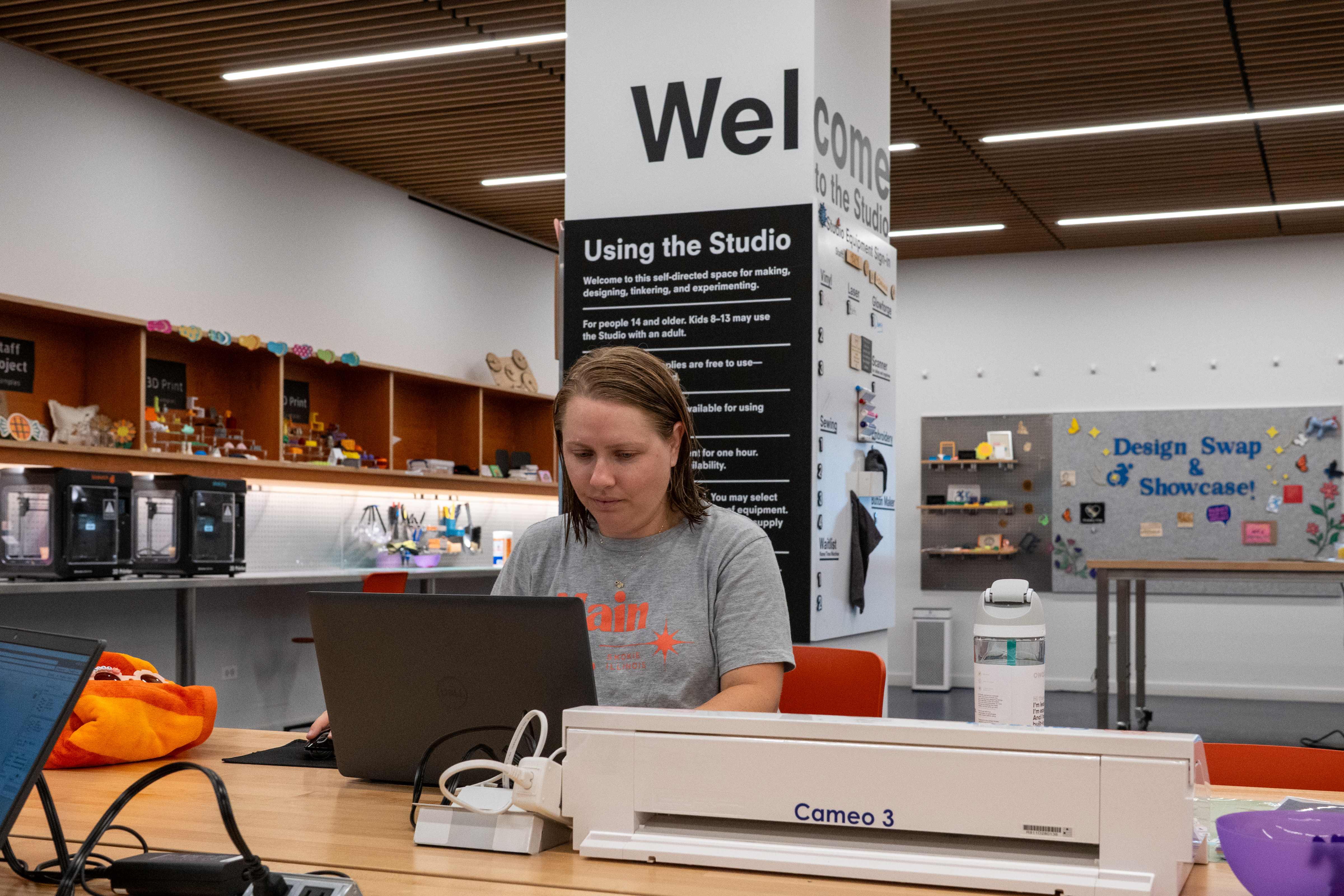 woman sitting in front of a computer next to a vinyl cutter