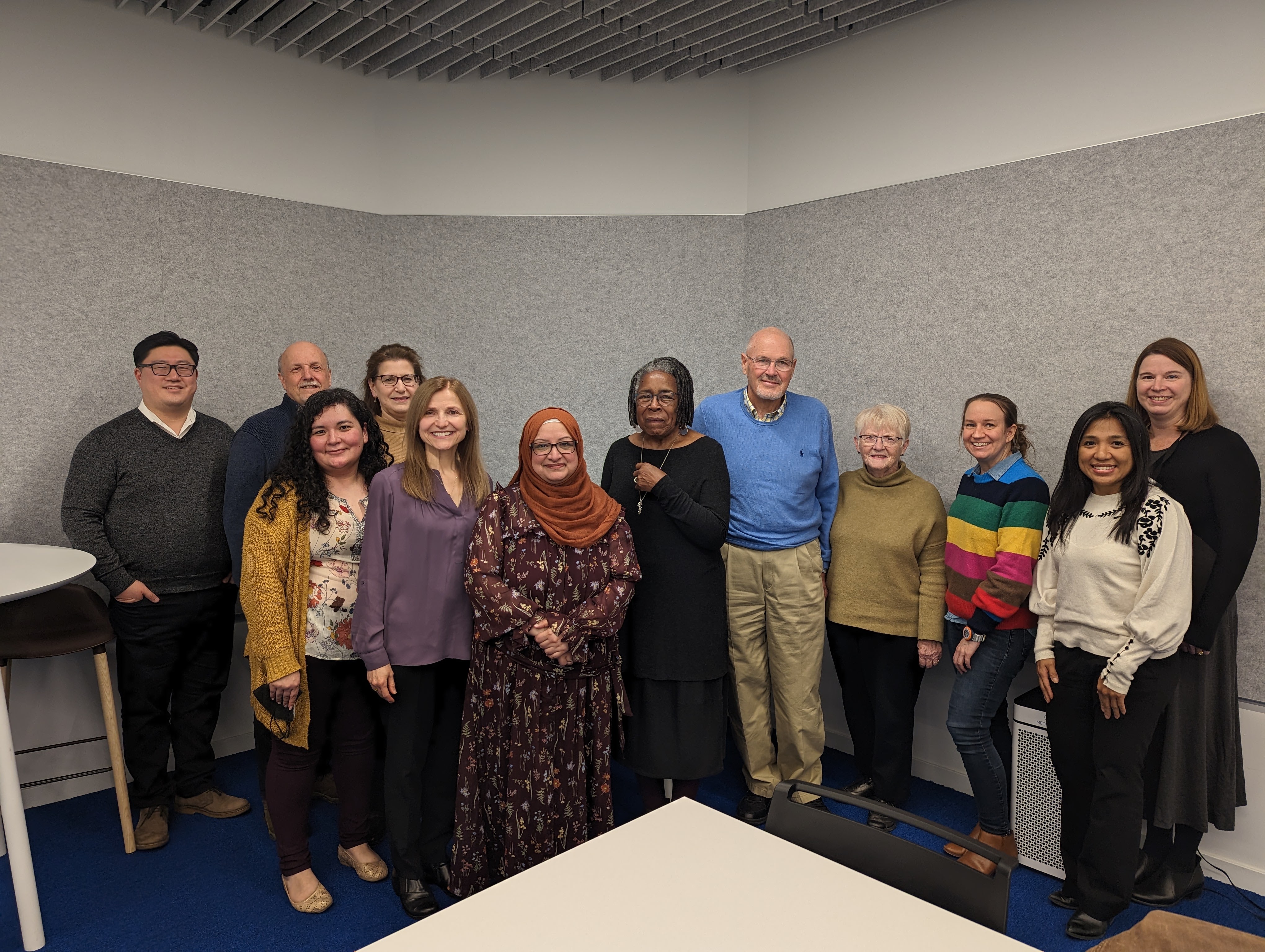 a group of people standing in a meeting room and smiling