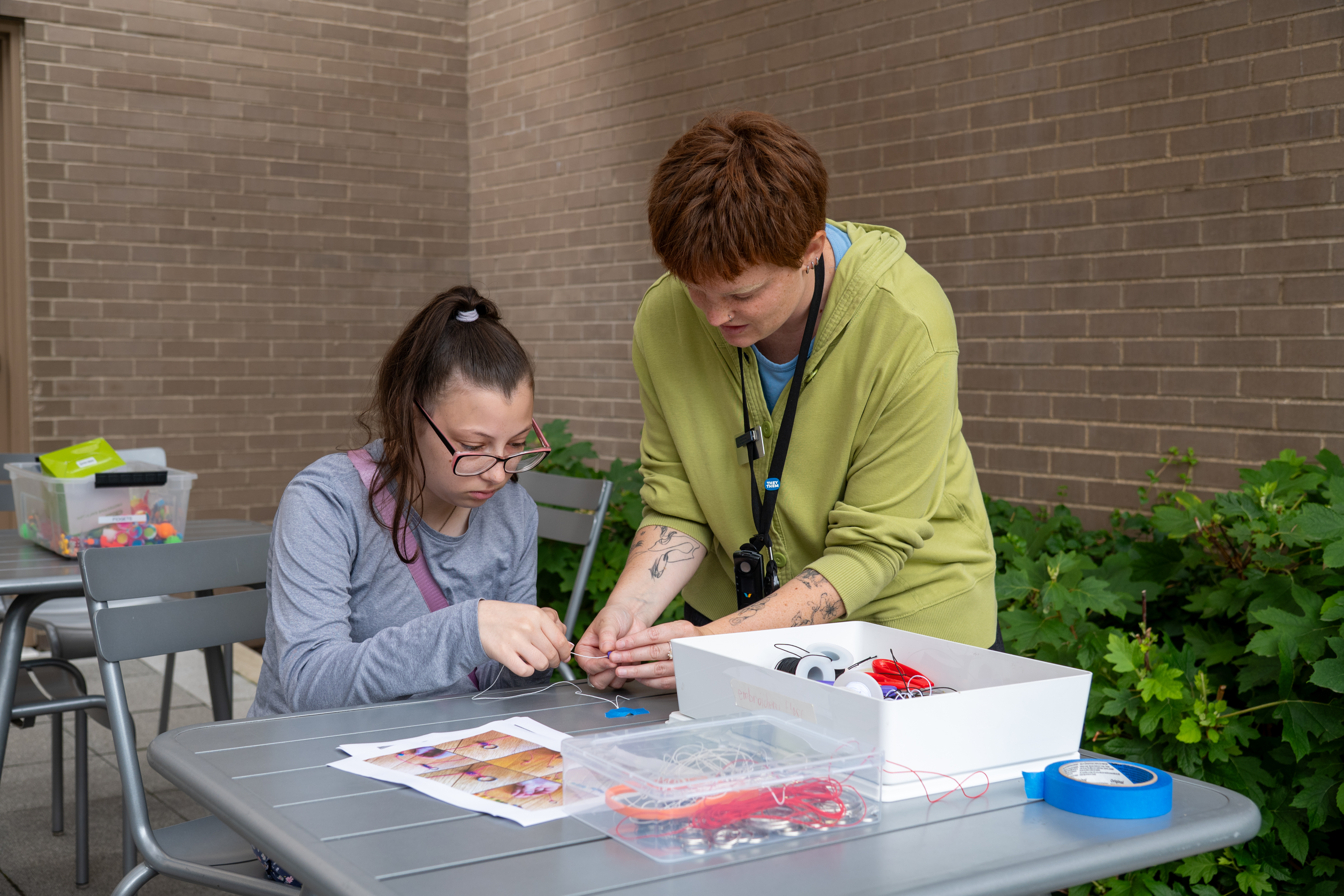 a library staff person helping a teen with a craft