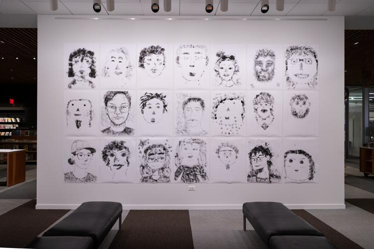 Black and white self-portraits displayed on a white wall