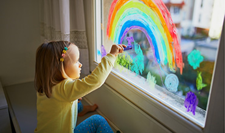 young child is drawing a rainbow on windows using chalk windows