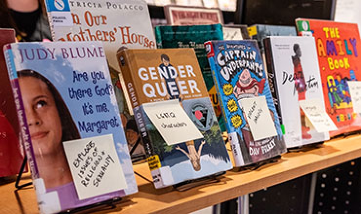 banned books on a table with post-it notes on each book explaining why each book was banned or challenged. 