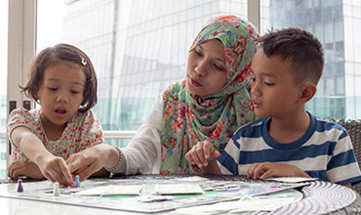 an adult woman and two kids playing a board game