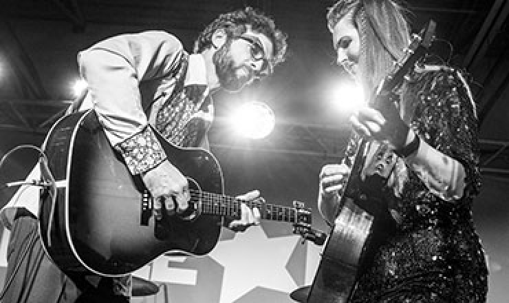 black and white photo of a man and woman playing guitars on a stage