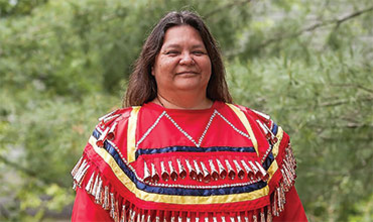 headshot of Kim Sigafus wearing Native regalia. 