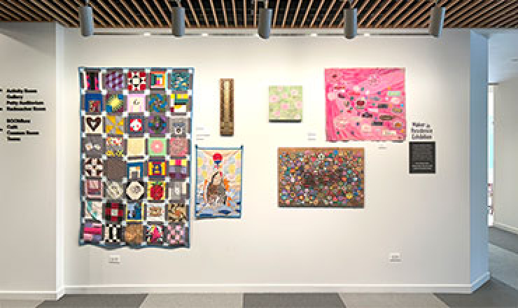 6 art pieces hanging from an interior wall in the library