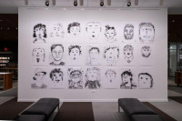 Black and white self-portraits displayed on a white wall