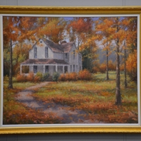 Painting in a gold frame of a white two story house with trees and fall leaves